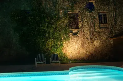 two chairs sitting next to a swimming pool at night at L'Impasse du Temple in Léran