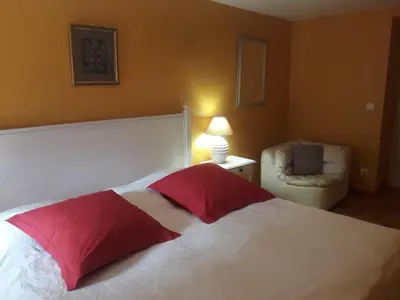 a bedroom with a bed with a red pillow and a chair at Gîte Roc Suzadou in Ferrals-les-Montagnes