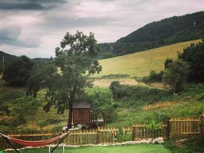 a hammock in a field with a tree and a fence at Gîte Tanagra : Maison avec piscine et vue exceptionnelle in Roquefort-les-Cascades