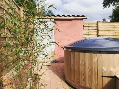 a large wooden tub sitting next to a fence at Gîte Aurinko : caravane avec bain nordique in Roquefort-les-Cascades