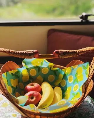 a basket of apples and bananas on a table at Gîte Aurinko : caravane avec bain nordique in Roquefort-les-Cascades