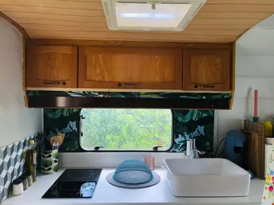 a kitchen with a sink and a window in a caravan at Gîte Aurinko : caravane avec bain nordique in Roquefort-les-Cascades
