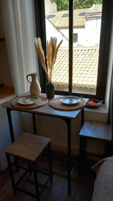 a table in a room with plates and a window at Le studio des halles avec climatisation 15m2 in Narbonne