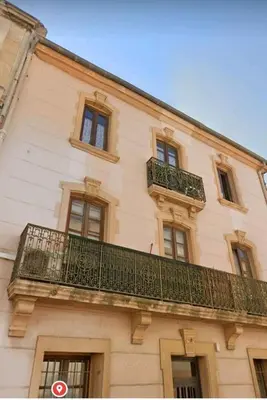 a building with a balcony on the side of it at Le studio des halles avec climatisation 15m2 in Narbonne