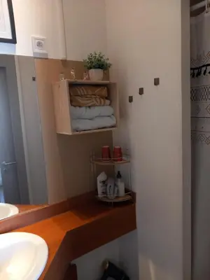 a bathroom with a sink and a shelf with towels at Le studio des halles avec climatisation 15m2 in Narbonne