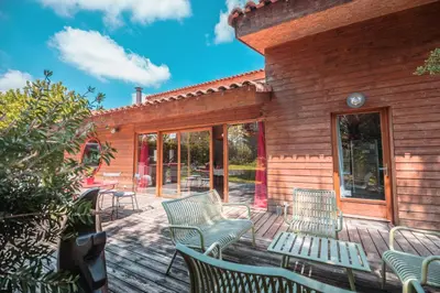 a deck with chairs and tables on a house at Chambre d’Hôtes Neptune Wood in Arzens