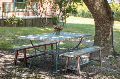a picnic table with a bench and a pot of flowers at Chambre d’Hôtes Neptune Wood in Arzens