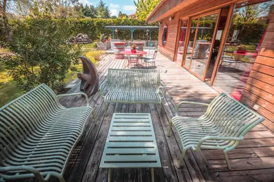 three green benches sitting on a wooden deck at Chambre d’Hôtes Neptune Wood in Arzens