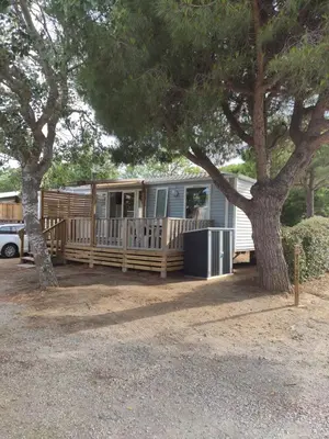 an rv parked under a tree in a yard at Mobilhome climatisé et ombragé in Port-la-Nouvelle