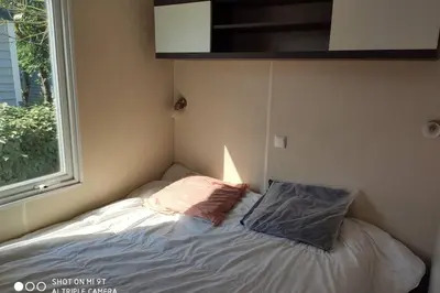 a small bed in a room with a window at Mobilhome climatisé et ombragé in Port-la-Nouvelle