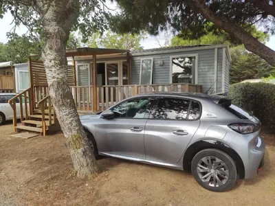 a car parked in front of a tiny house at Mobilhome climatisé et ombragé in Port-la-Nouvelle