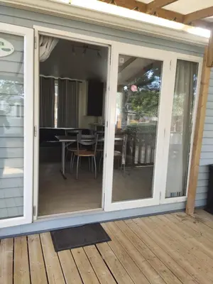a screened porch with sliding glass doors on a deck at Mobilhome climatisé et ombragé in Port-la-Nouvelle
