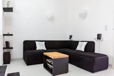 a living room with a black couch and a table at Opuntia (Pech) location en Méditerranée in Escales