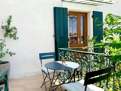 a table and chairs on a balcony with a green door at Villa Saint Léon in Badens
