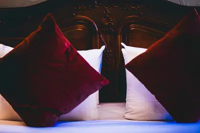 a bed with red and white pillows on it at La Maison de L' Ambassadeur Carcassonne B&B in Carcassonne