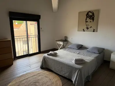 a bedroom with a bed and a large window at L'atelier in Capestang