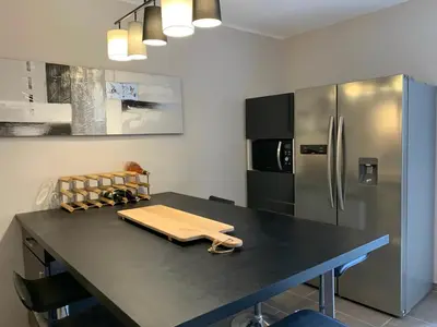 a kitchen with a table and a refrigerator at Sur la Terrasse in Sigean