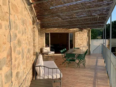 a patio with a table and chairs and a stone wall at Chez Noisette in Durban-Corbières