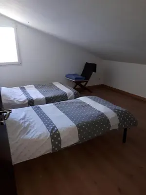 two beds in a small room with a chair at La Sigeannaise maison climatisée Wi-Fi in Sigean