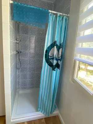 a shower with a blue shower curtain in a bathroom at RIBES - Chalet Gîte au coeur de la nature in Sournia