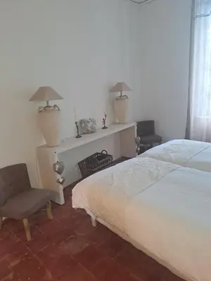a bedroom with a white bed with a painting on the wall at Le gîte de Sainte Valière PISCINE,SPA et CLIMATISATION in Sainte-Vallière
