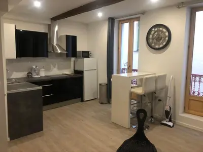 a kitchen with black and white appliances and a table at Appartement Plein centre in Narbonne