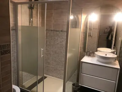 a bathroom with a glass shower and a sink at Appartement Plein centre in Narbonne