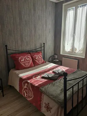 a bedroom with a bed with red pillows and a window at Chambres d'hôtes Natacha et Franck in Labastide-Rouairoux