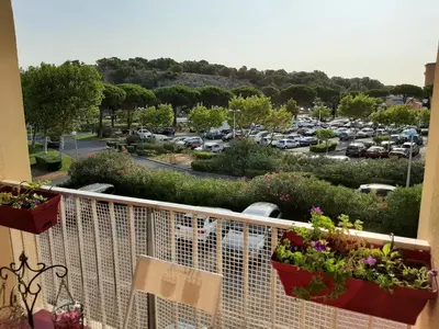 a balcony with some plants and a parking lot at Entre port et village in Gruissan