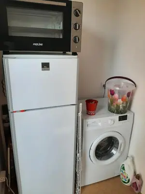 a microwave on top of a refrigerator next to a washing machine at Entre port et village in Gruissan