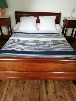 a bed with a wooden frame in a bedroom at MAISON ALBA LA SOURCE in Mazamet
