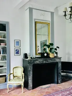 a living room with a mirror and a chair at Le Domaine de Villespy in Villespy