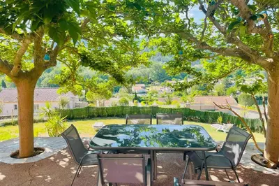 a table and chairs under a tree in a yard at Charmante maison avec jacuzzi in Montazels
