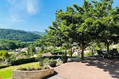 a patio with a tree and a table and chairs at Charmante maison avec jacuzzi in Montazels