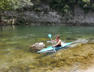 a boy on a paddle board in the water at Chambre d'hôtes Le Rougeyras in Roquebrun