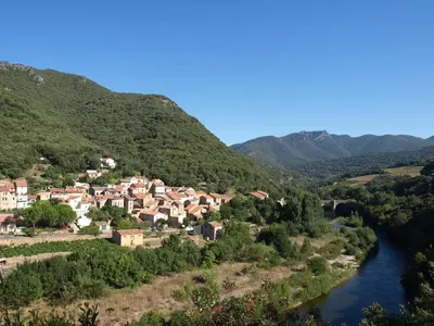 a small village on a hill next to a river at Chambre d'hôtes Le Rougeyras in Roquebrun