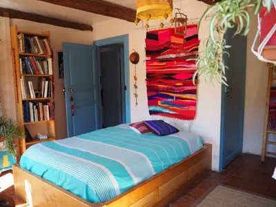 a bedroom with a bed with colorful clothes hanging on the wall at Chambre d'hôtes Le Rougeyras in Roquebrun