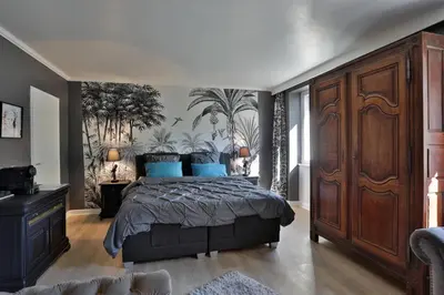 a bedroom with a large bed with blue pillows at La Chapelle aux Acacias in Caucalières