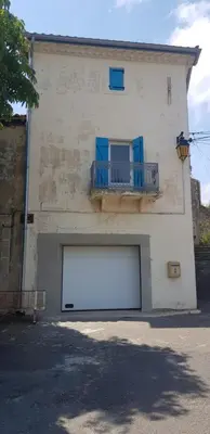 a white building with a large white garage at Maison au milieu des vignes in Aigues-Vives