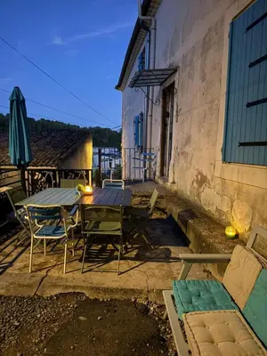 a patio with a table and chairs and an umbrella at Maison au milieu des vignes in Aigues-Vives