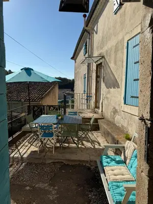 a patio with a table and chairs and an umbrella at Maison au milieu des vignes in Aigues-Vives