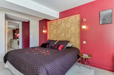 a bedroom with a large bed and red walls at Les Gîtes de Laure - O Lit Divin, Instant de volupté, BALNEO SAUNA, Climatisation, Netflix, 160m de la Cité Médiévale in Carcassonne