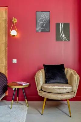 a living room with a chair and a red wall at Les Gîtes de Laure - O Lit Divin, Instant de volupté, BALNEO SAUNA, Climatisation, Netflix, 160m de la Cité Médiévale in Carcassonne