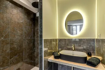 a bathroom with a sink and a mirror at Les Gîtes de Laure - O Lit Divin, Instant de volupté, BALNEO SAUNA, Climatisation, Netflix, 160m de la Cité Médiévale in Carcassonne