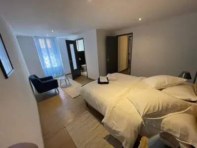 a bedroom with a large white bed and a chair at La pause du canal in Trèbes