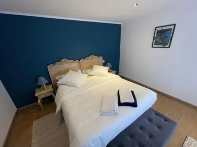 a bedroom with a large bed with a blue wall at La pause du canal in Trèbes