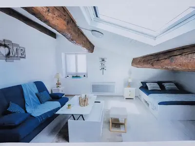 a white living room with a blue couch and a bed at STUDIO 9 Classé 2 Etoiles in Carcassonne