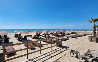 a beach with people sitting at tables and chairs at Le Bariole, luxury villa with heated pool in Cesseras