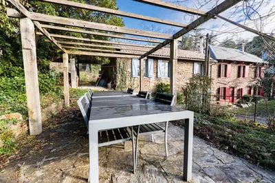 a picnic table with benches sitting under a pergola at La Rustique, maison de charme proche Carcassonne - jardin, wifi, tout équipée in Cuxac-Cabardès