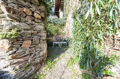 a stone wall with a bench in a garden at La Rustique, maison de charme proche Carcassonne - jardin, wifi, tout équipée in Cuxac-Cabardès